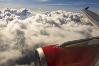 A colour landscape image looking out through airplane window showing land, cloud and sky