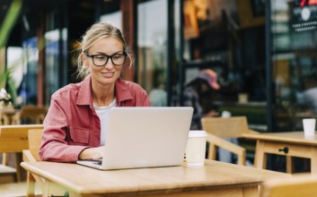 Young attractive caucasian woman sitting in a cafe works on a laptop