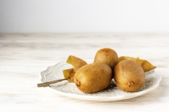 Ripe kiwis lie on a white ceramic plate, selective focus