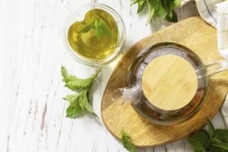 Cup and teapot of fresh natural herbal tea with fresh mint leaves on rustic wooden table. Organic