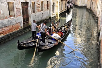 Venice, Veneto, Italy, Europe, Gondolas manoeuvre through a narrow canal, surrounded by old brick