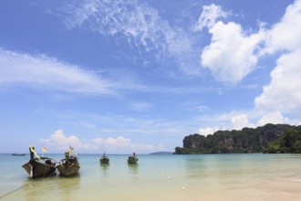 Light cirrus clouds over the warm sea. Picturesque native boat Longtail waiting on the beach the