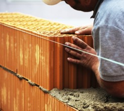 Anonymous construction worker on a building site erecting a brick wall. Brick wall of a solid house