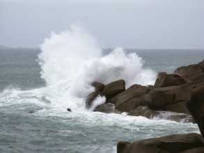 Strong surf waves break on a rocky outcrop