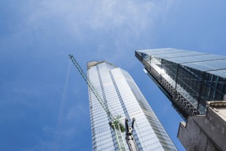 London, UK, May 14, 2019: Low angle view of skyscraper with cranes under construction in the City
