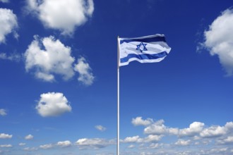 Flag of Israel fluttering in the blue sky with cumulus clouds