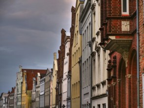 A row of historic red brick buildings under a cloudy sky, gothmund, travemünde, lübeck, germany