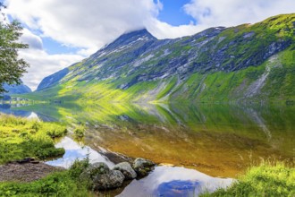 Deep lake with clean transparent water. The water reflects lush clouds, blue skies and forested