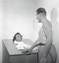 Beauty care in the 1950s. A young woman is sitting in a steam sauna, with only her head sticking up