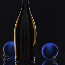 The bottle of red wine and Christmas decoration on a black glass desk