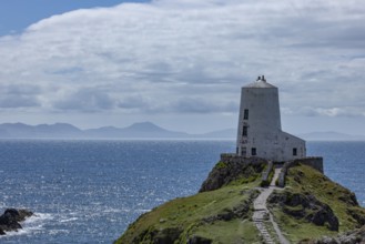 Twr Mawr Lighthouse, white lighthouse on a hill by the sea with blue sky and clouds, Ynys