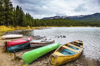 Multicolored boats and canoes dry on the lakeside. Cold cloudy fall day in the Canadian Rockies.