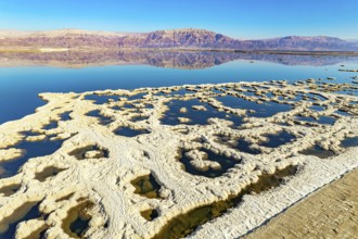 Evaporated salt forms bizarre patterns on the water. Dead Sea. The blue water is surrounded by pink