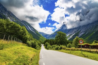 Scenic road in the mountains. Wonderful fresh green vegetation and lush snow-white clouds. Travel
