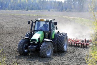 Farmer cultivating field with green Deutz-Fahr Agrotron 135 tractor and Vaderstad NZ aggressive