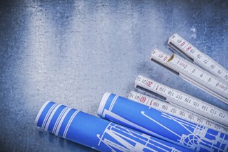 Blue rolled construction drawings wooden meter on scratched metallic background