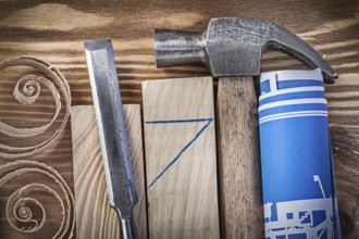 Blue rolled construction drawing claw hammer firmer chisel wooden studs curled shavings on vintage