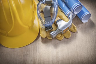 Protective work wear claw hammer rolled construction plans on wooden board
