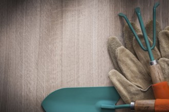 Leather gardening gloves hand spade and rake on wooden board agriculture concept