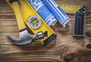 Blue blueprints construction level try square claw hammer on wooden board