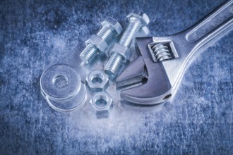Metal adjustable wrench bolt washers screw-nuts and screwbolts on scratched metallic background