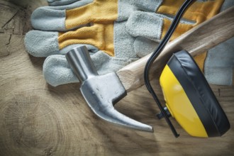 Claw hammer protective gloves earmuffs on wooden board