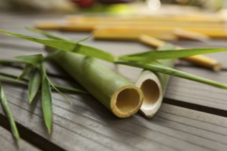 Round bamboo sticks with leaves on wooden background. Ecological raw material