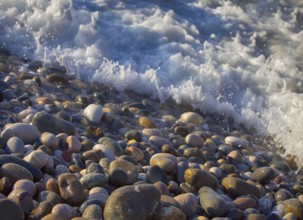 Beach of multi-colored round pebbles, and the splash of salty waves. Black sea, Caucasus