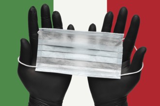 Doctor holds face mask in hands in black medical gloves on background colors flag of Italy or