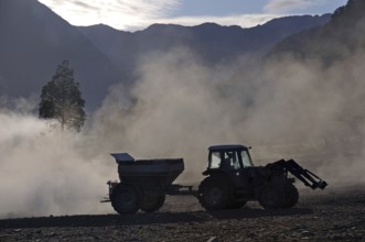 Tractor spreading lime with a fertiliser spreader, West Coast, New Zealand