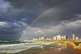 Storm cloud hanging over the sea, gorgeous huge rainbow crossed the sky. Promenade and beach in Tel