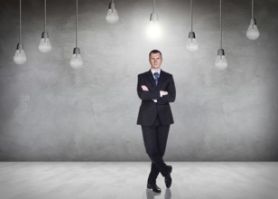 Businessman stands in a gray room with hanging bulbs