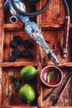 Dismantled parts of the hookah in stylish wooden box with fruits lime