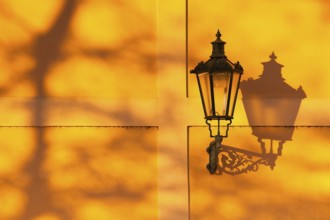 Detail of retro street light on the wall at sunset. Prague, Czech Republic