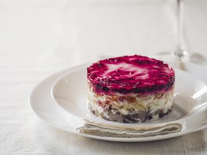 Layered salad herring under fur coat on table. Portion of traditional russian salad with herring,