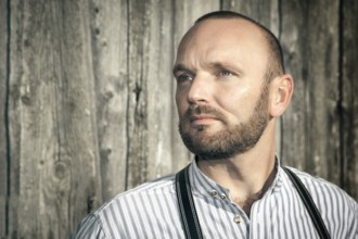 A traditional bavarian man in front of a wooden background
