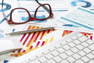 Business workplace with keyboard glasses and financial documents on table