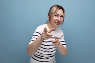Nahaufnahme einer energetischen blonden jungen frau in einem gestreiften pullover auf einem blauen