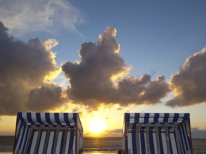 Two empty beach chairs enjoy the view of a golden sunset, norderney, north sea, germany