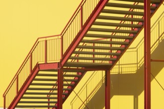 Red metal outdoor stairway in front of yellow wall