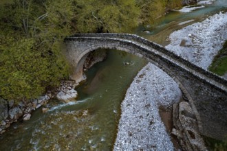 Drone aerial of Ancient, stoned, arched bridge St. Vissarion on the Portaikos river in autumn.
