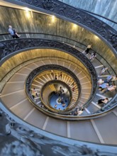 Aerial view of a busy spiral staircase with people ascending and descending, highlighting the