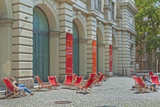 Red deckchairs and advertising banners on cobblestones in front of the Literaturhaus, Munich,