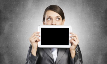 Businesswoman holding tablet computer with blank screen. Beautiful woman in business suit show