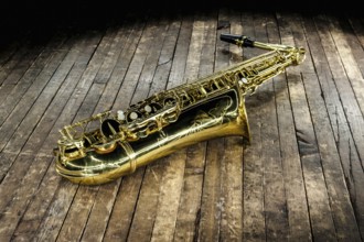 Beautiful golden saxophone lies on a wooden floor