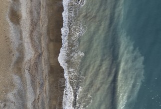 Drone aerial view of stormy ocean waves breaking on a sandy beach. Nature background