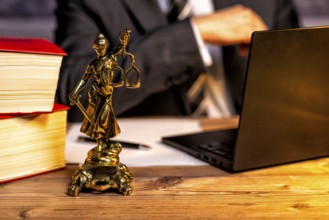 Office of a lawyer with books and a statue of Lady Justice, goddess Justitia, on the desk