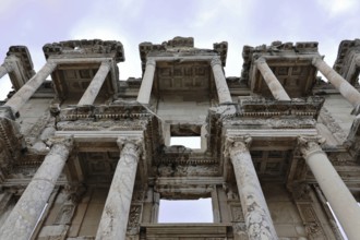 Ruins of an ancient library with impressive marble columns and detailed decorations under a blue