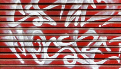 Red garage gate with vandalism sign of graffiti white spray paint. Ideal for concepts and