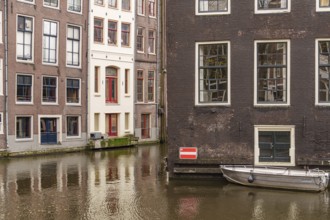 Quiet canal surrounded by traditional buildings with a small boat, Amsterdam, Netherlands